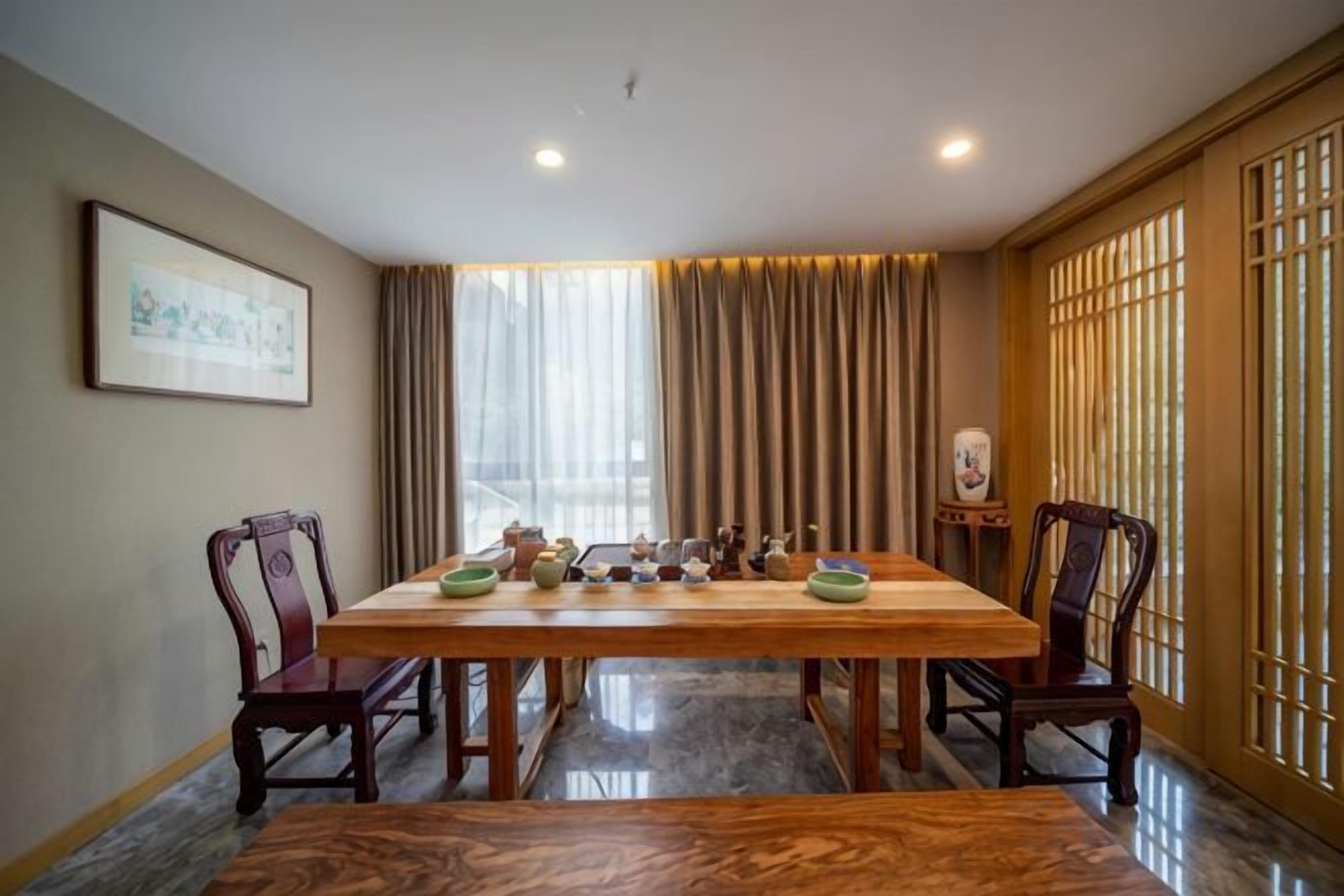 A dining area with a wooden table, chairs, and a vase on a side table.