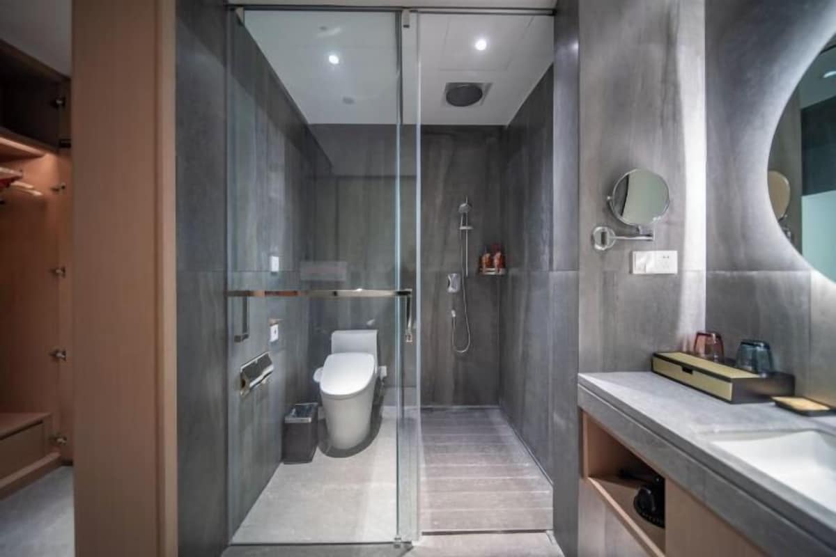 A modern bathroom with a glass-enclosed shower, a toilet, and a vanity with a mirror.