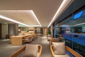 A modern hotel lobby with a long reception desk, seating area, and large windows offering a view of the street. - Shenxianju Narada Resort (Xianju)
