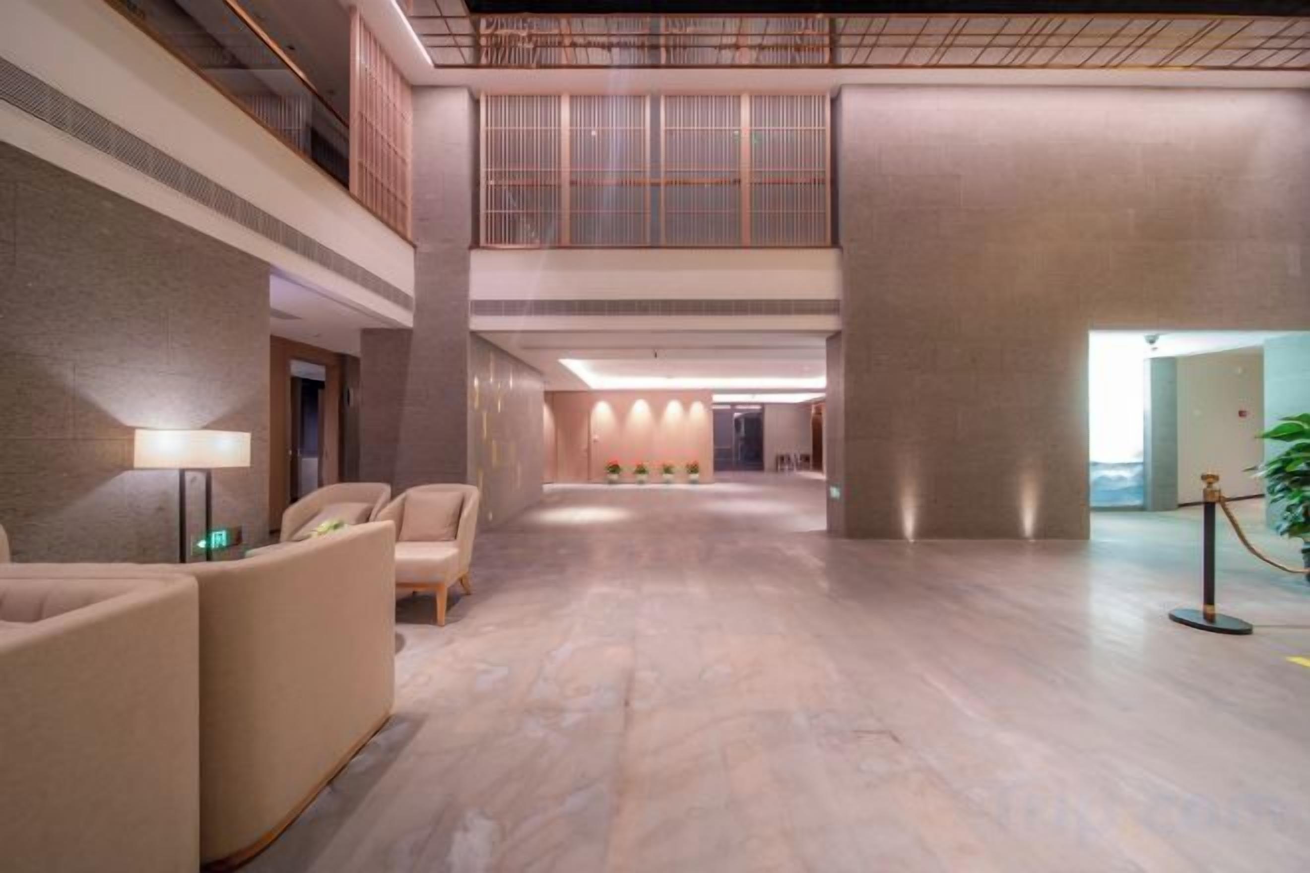 A spacious lobby with a high ceiling, a reception desk, and a seating area.