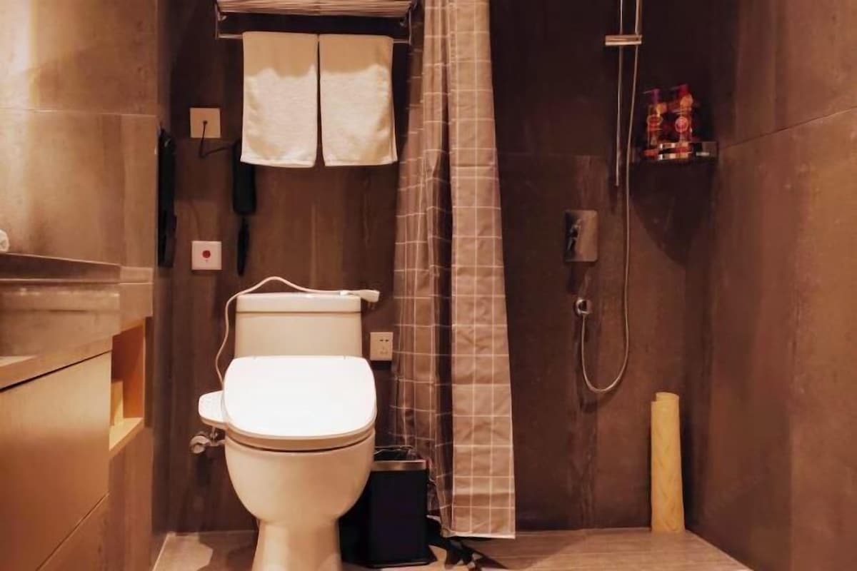 A bathroom with a toilet, a shower, and a towel rack.