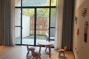 Una habitación con puerta corrediza de vidrio que da a un patio, una mesa redonda de madera y dos sillas.