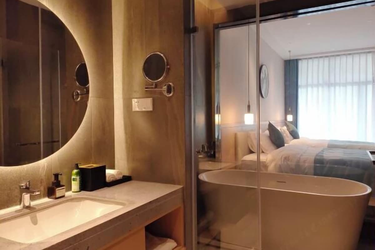 A modern bathroom with a large mirror, a sink, and a bathtub.