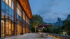 Un edificio moderno con amplios ventanales y un patio con mobiliario exterior.