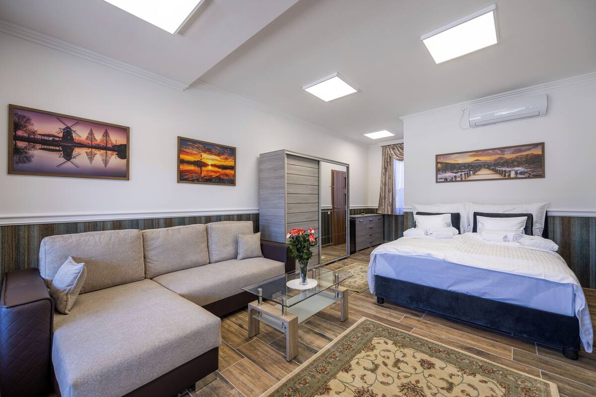 A modern bedroom with a bed, a sofa, a glass coffee table, and a wardrobe.