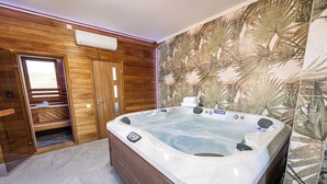 Un baño moderno con tocador de madera, una bañera grande y un papel tapiz con estampado de hojas tropicales.