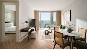 A modern hotel room with a city view, a dining area with a round table, and a separate bedroom with a bed and a desk. - Epic Tower Swiss-Belresidences Hanoi (Hanoi)