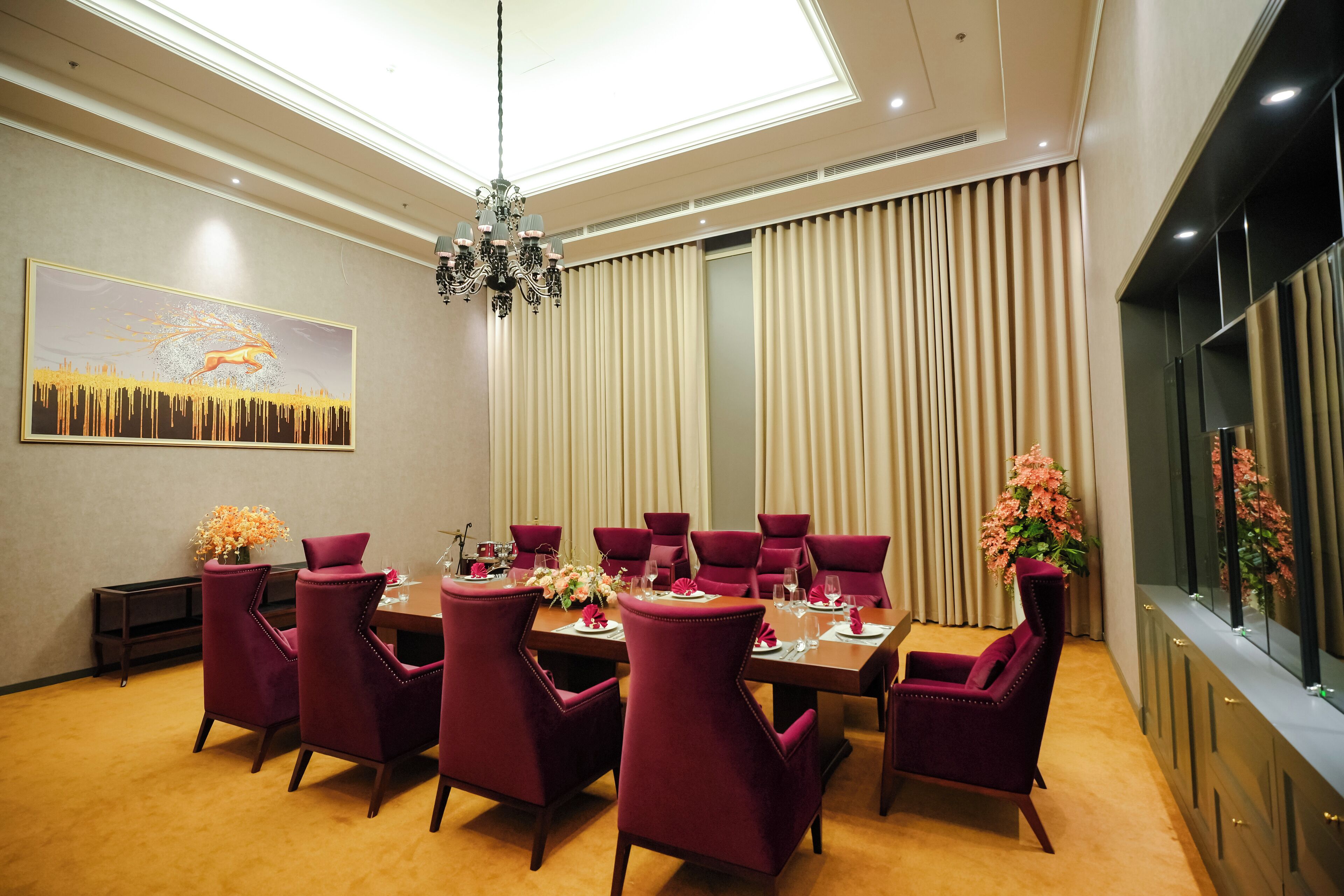 A dining area with a long table, multiple chairs, and a chandelier.