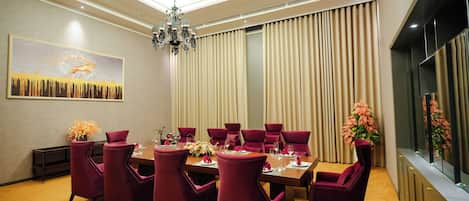 A dining area with a long table, multiple chairs, and a chandelier.