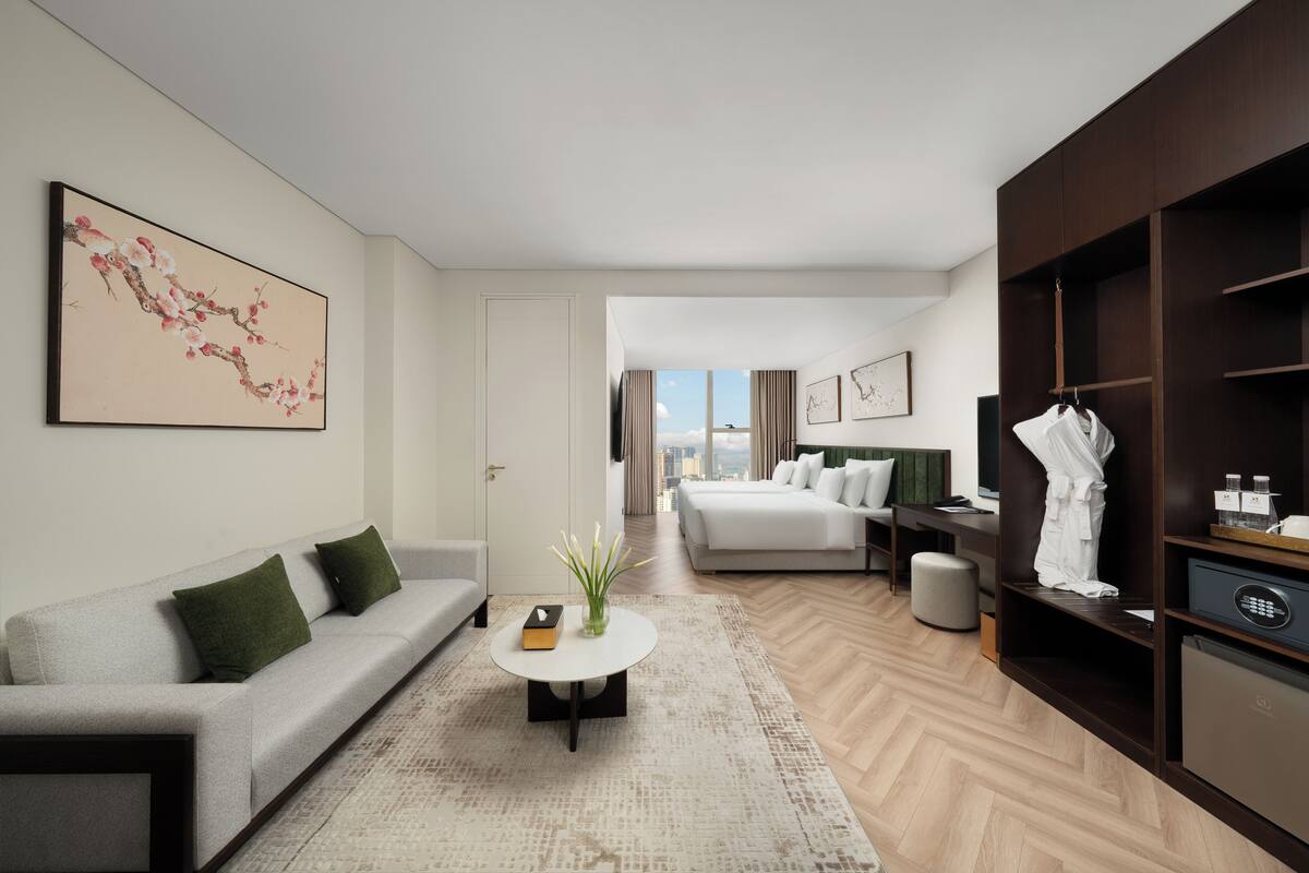 Una habitación de hotel moderna con sofá, una mesa redonda, cama, armario y vistas a la ciudad.