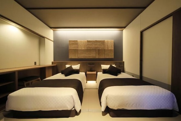 A hotel room with two beds, a desk, and a wall-mounted panel. - Kusatsuonsen Aeruyadotakamatsu (Kusatsu)