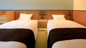 Een hotelkamer met twee bedden, houten hoofdeinden en een klein nachtkastje.