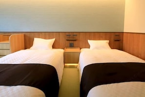 A hotel room with two beds, wooden headboards, and a small bedside table. - Kusatsuonsen Aeruyadotakamatsu (Kusatsu)
