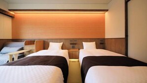 Een hotelkamer met twee bedden, een houten hoofdbord, een nachtkastje en een klein bureau.