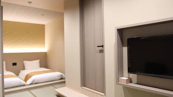Quarto de hotel com duas camas, televisão e porta de correr.