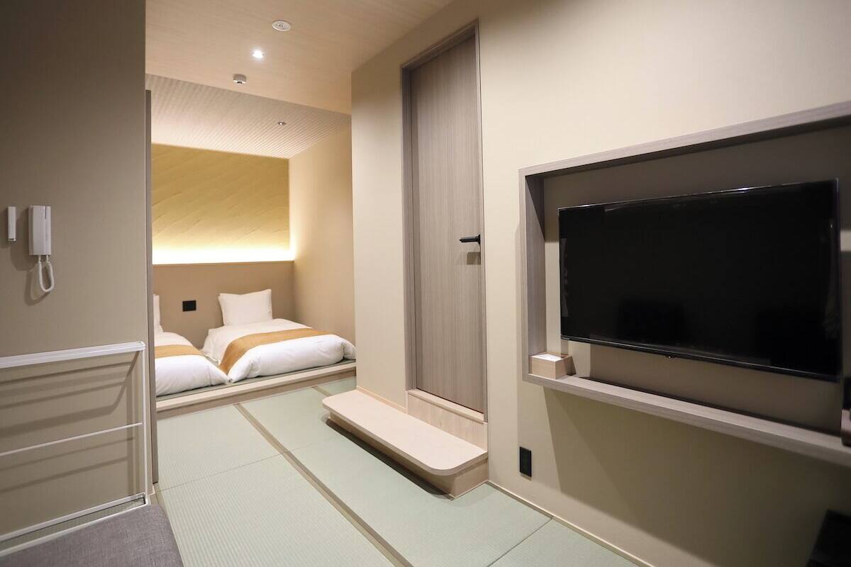 A hotel room with a bed, a TV, a phone, and a small seating area.
