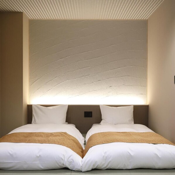Ein Hotelzimmer mit einem großen Bett, zwei Kissen und einer strukturierten Wandverkleidung darüber.