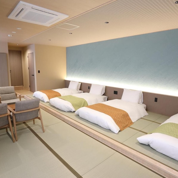 Una habitación de hotel con cama, mesitas de noche, una silla y un aire acondicionado de pared.