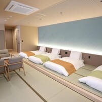 Una habitación de hotel con cama, mesitas de noche, una silla y un aire acondicionado de pared.