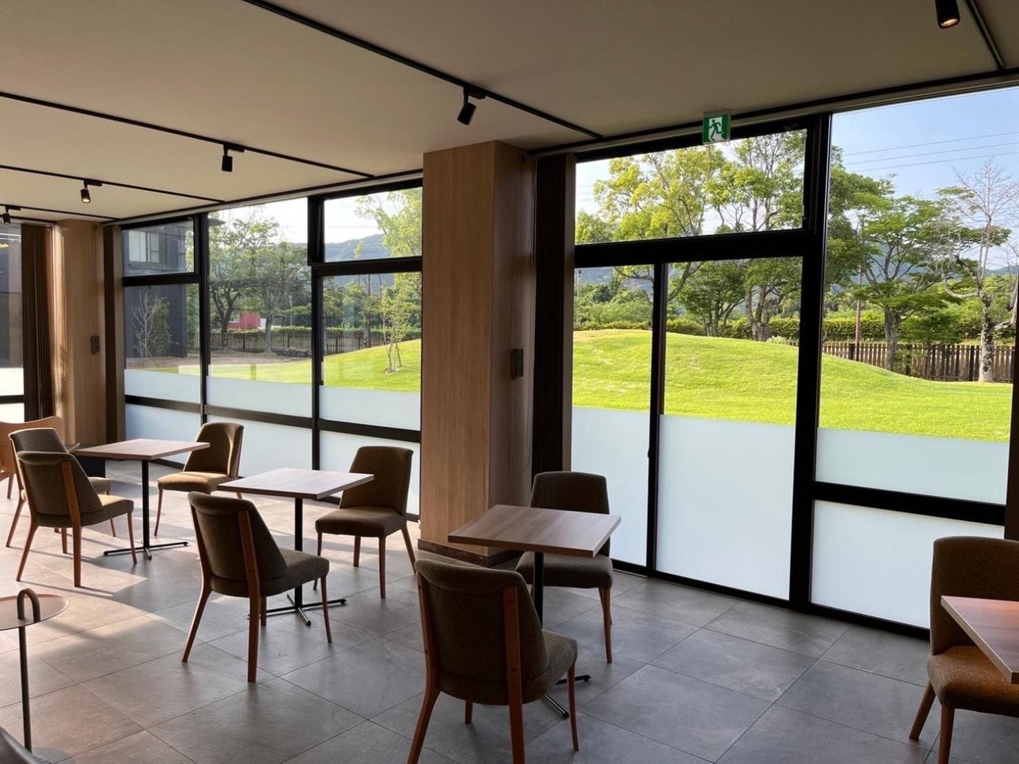 A modern indoor seating area with large windows, tables, and chairs.
