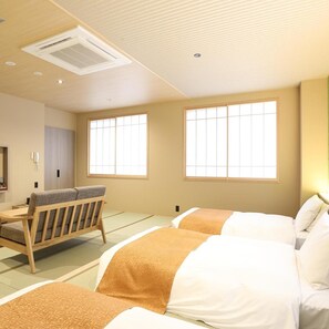 Quarto de hotel com tatames, futon, escrivaninha e janela no estilo tradicional japonês.