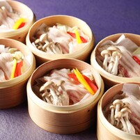Varias vaporeras de bambú con ingredientes frescos.
