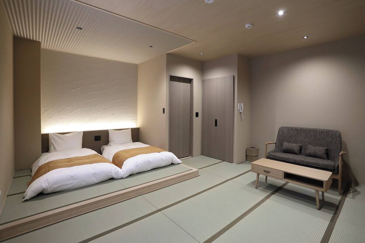 A hotel room with a bed, a sofa, a small table, and a wardrobe.