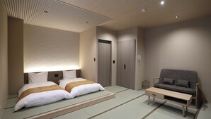 A hotel room with a bed, a sofa, a small table, and a wardrobe. - Miyawaka Torano Yu (Miyawaka)