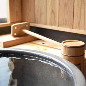 Um banco de madeira e um barril de madeira, provavelmente para armazenar água, em um espaço de sauna.