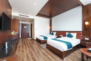 Ein Hotelzimmer mit zwei Betten, einem Fernseher, einem Schreibtisch und einem Badezimmer.