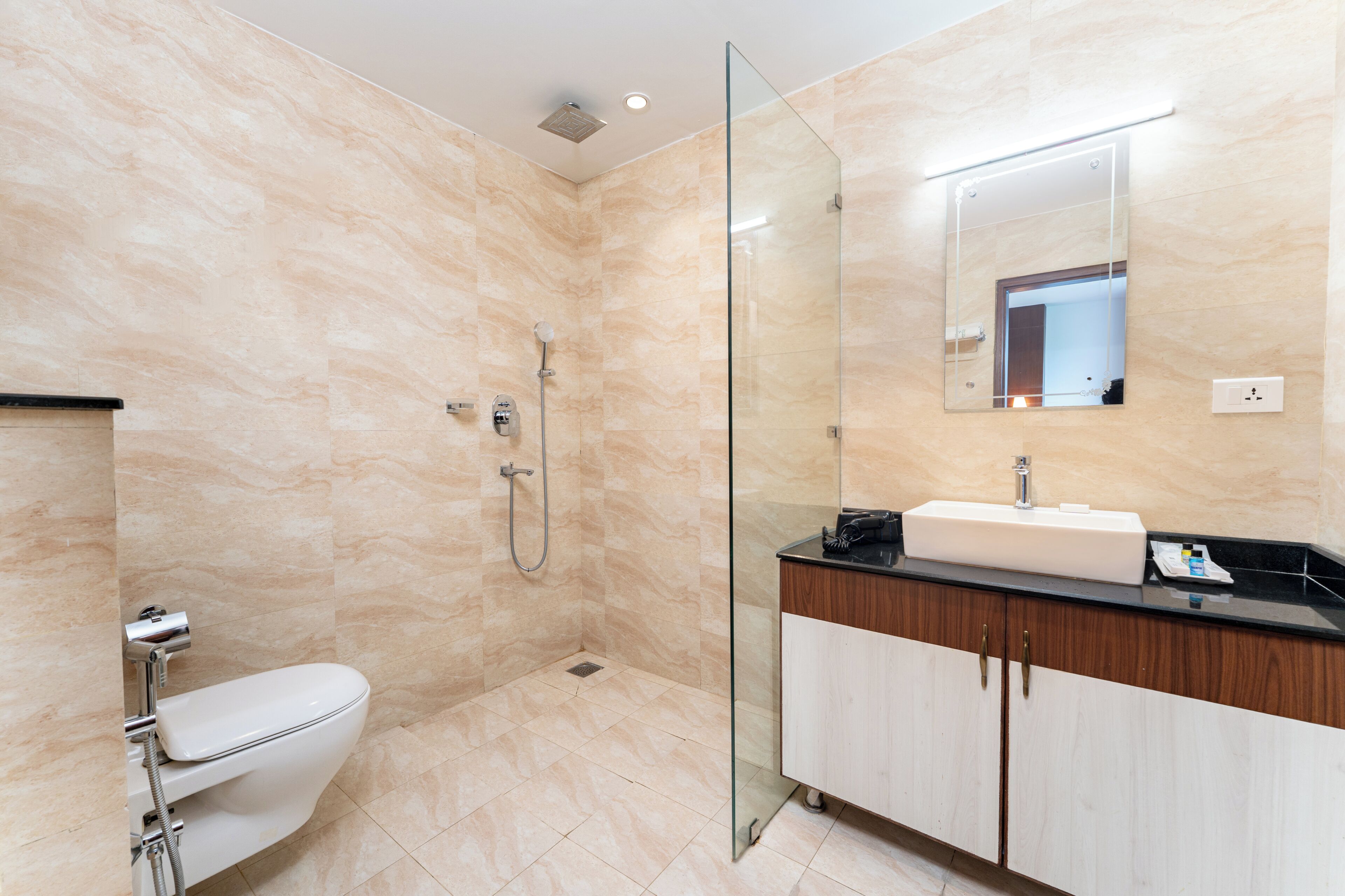 A modern bathroom with a glass shower enclosure, a white toilet, and a vanity with a mirror.