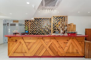 Een receptiebalie met een houten ontwerp, een glazen scheiding en een bordje dat een loungehoek aangeeft.
