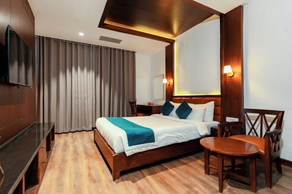 Een hotelkamer met een houten bed, een televisie, een bureau en een stoel.