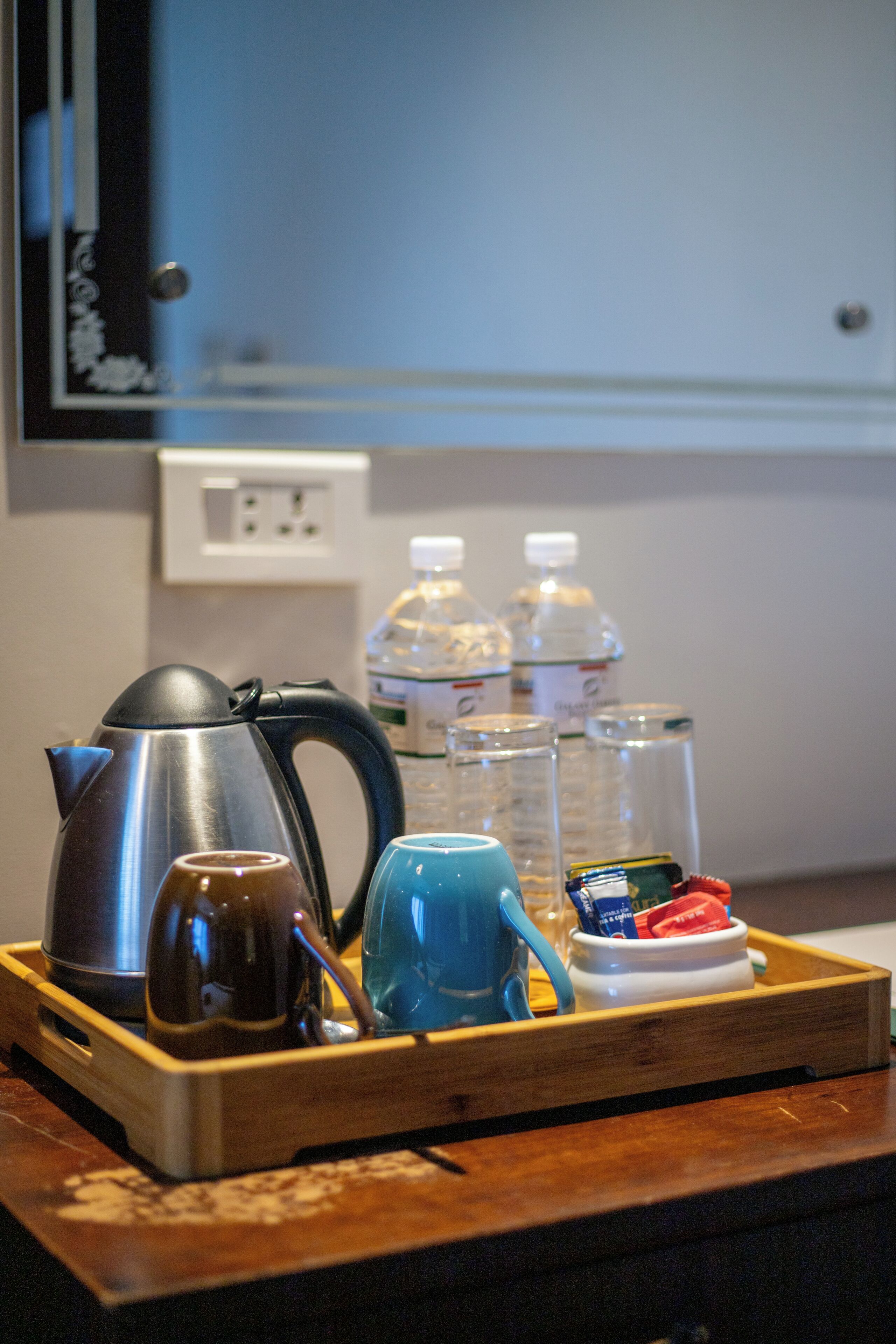Una bandeja con una tetera, taza y botellas de vidrio sobre una mesa de madera.