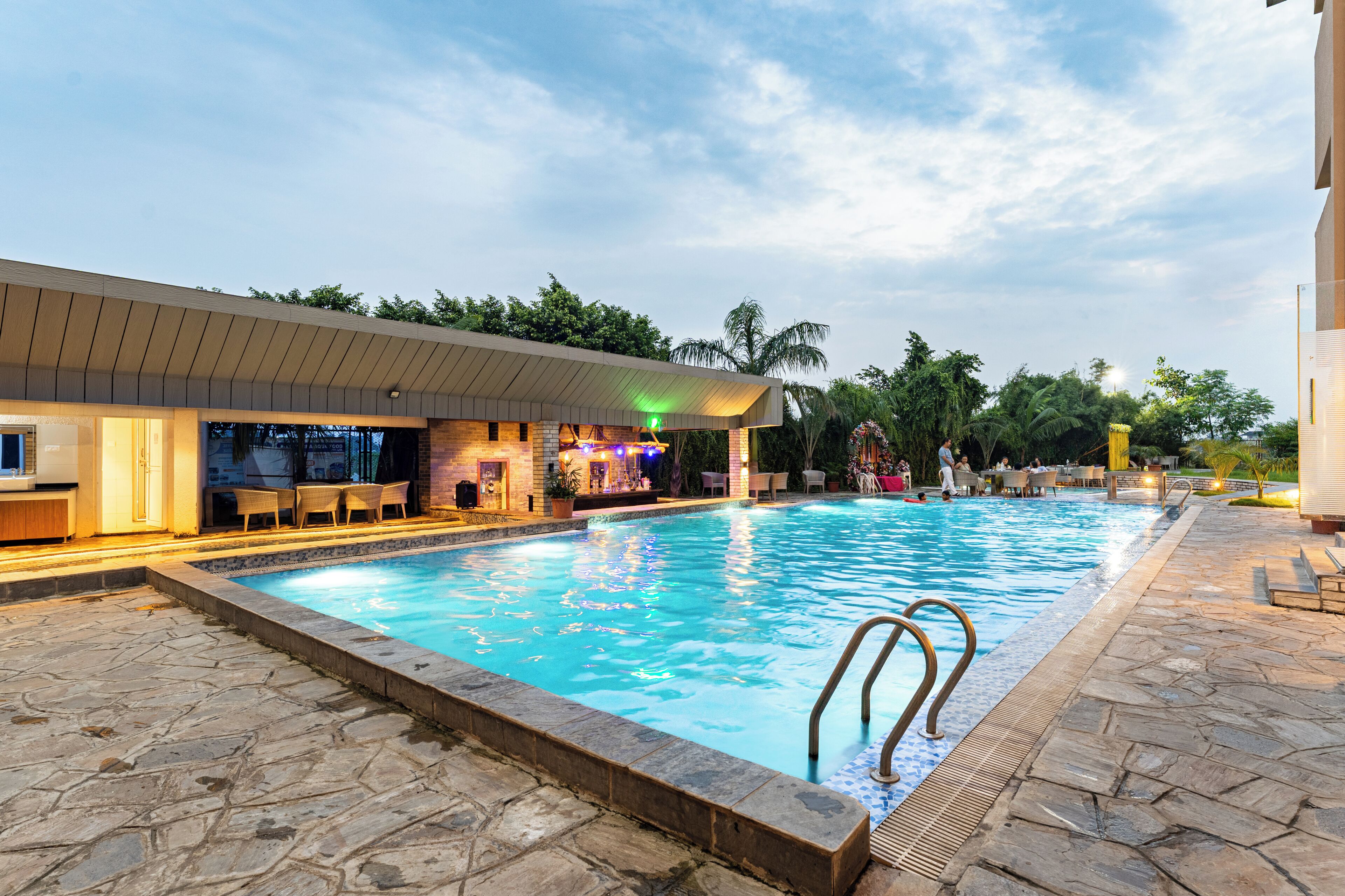 Una piscina con zona de bar y mobiliario exterior.