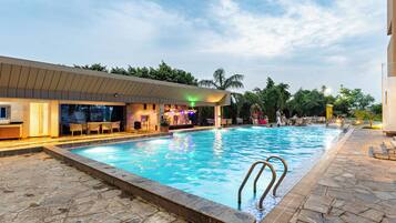 Una piscina con zona de bar y mobiliario exterior.