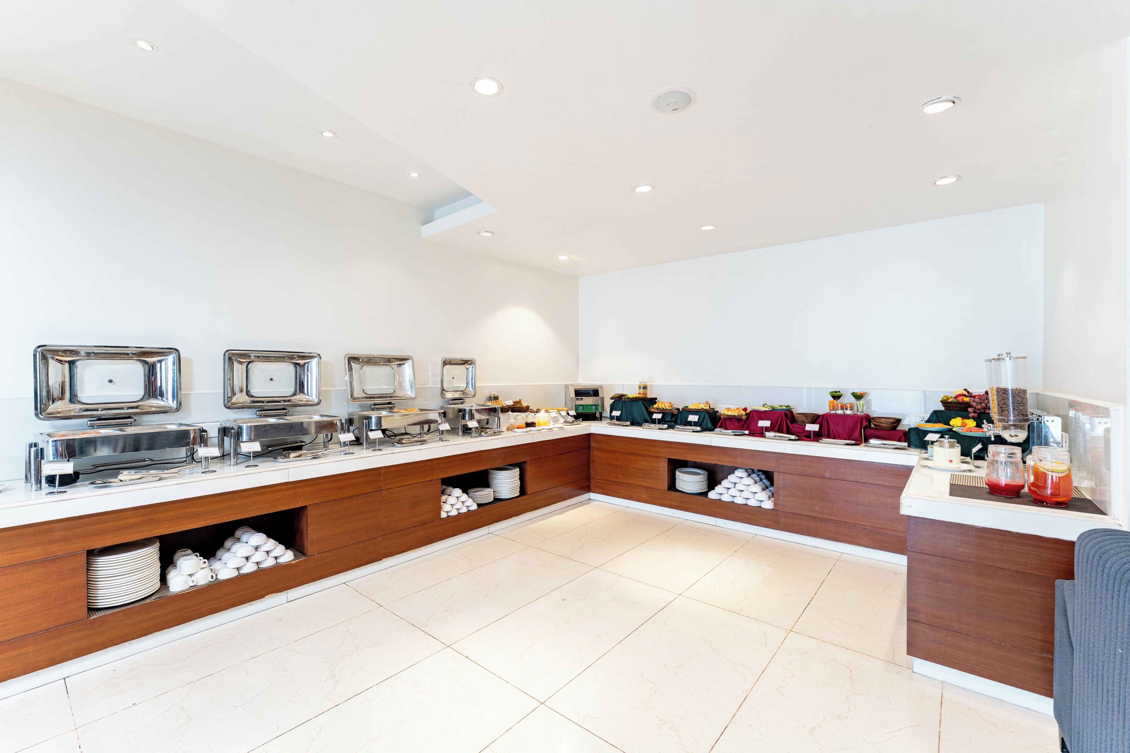 A modern breakfast buffet with multiple serving stations, a coffee machine, and a variety of food options.