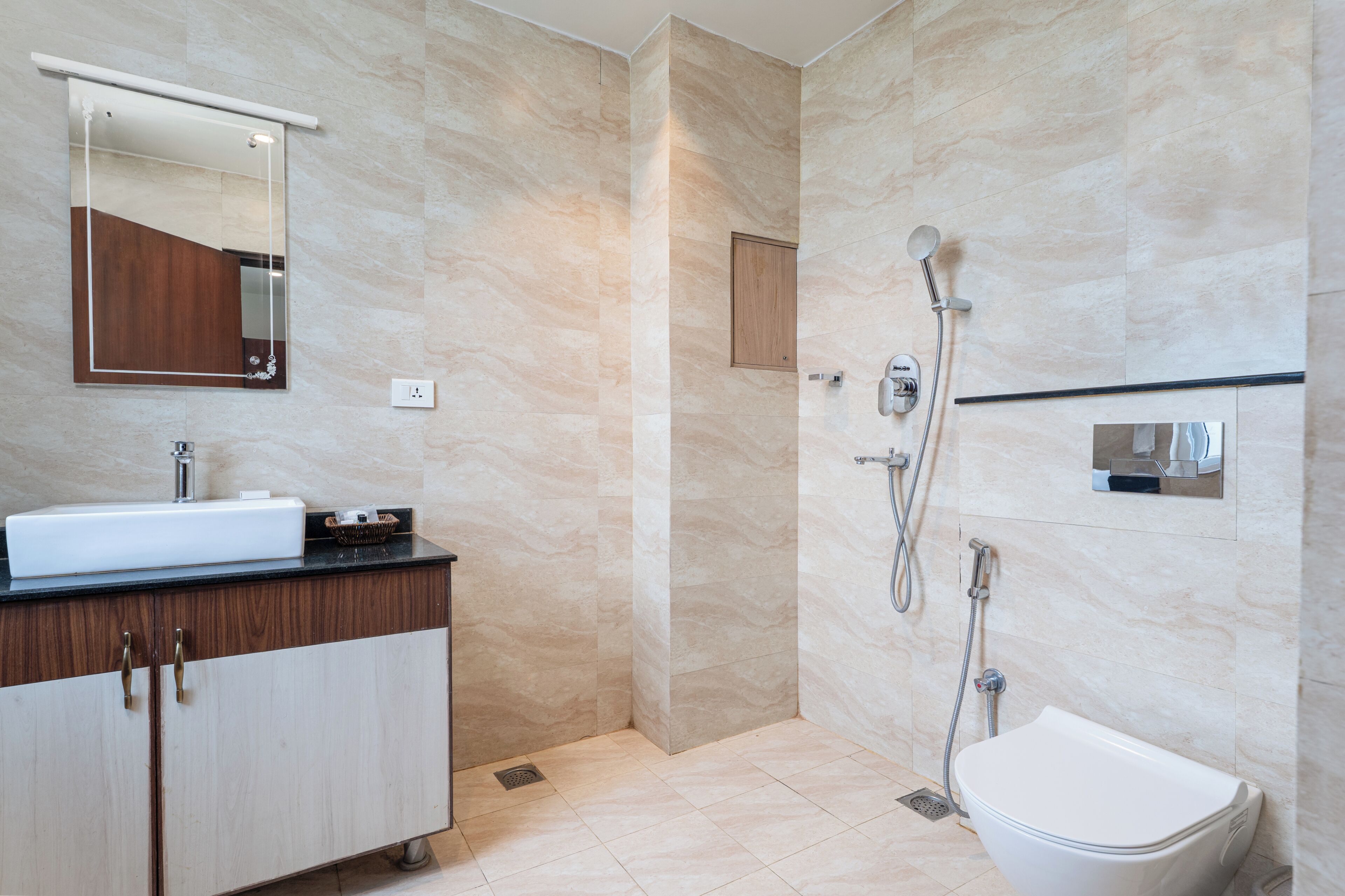 A modern bathroom with a sink, mirror, shower, and toilet.