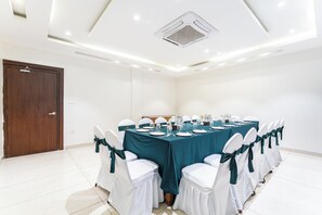 Ein Konferenzraum mit einem langen Tisch, weißen Stühlen mit türkis-farbenen Schals und einer türkis-farbenen Tischdecke.