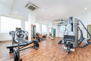 Une salle de sport moderne équipée de divers appareils d’exercice, dotée de grandes fenêtres et d’un plancher en bois.