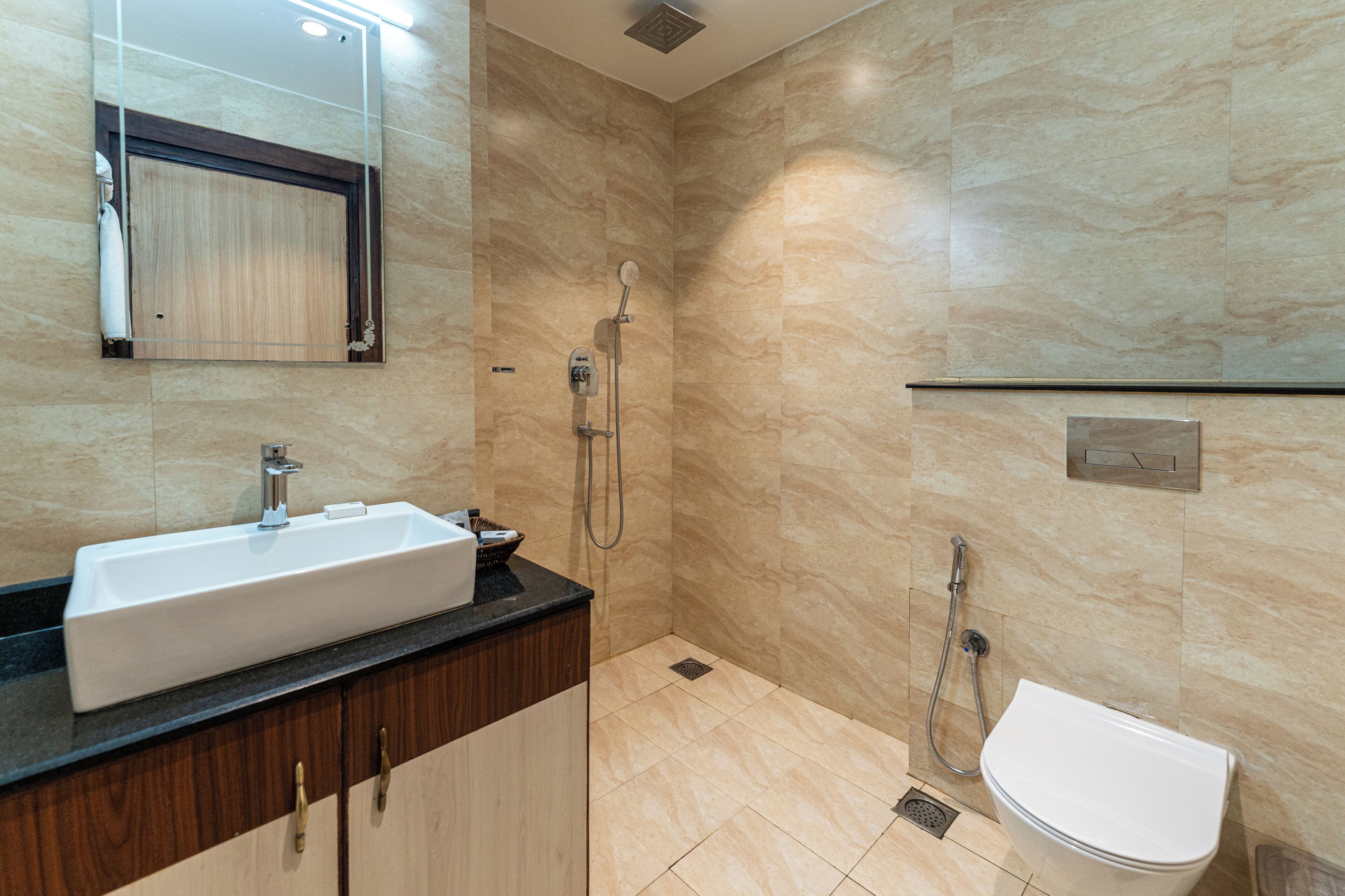 Un baño con lavamanos, espejo, ducha e inodoro.