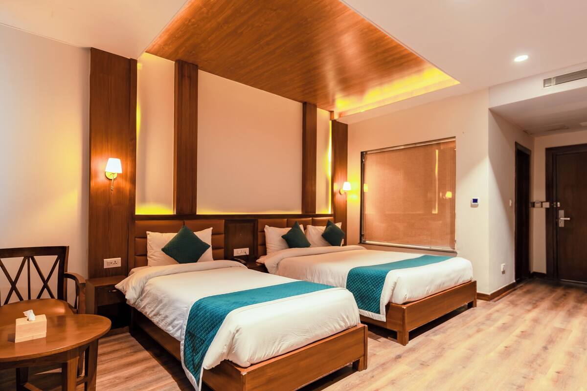 Een hotelkamer met twee bedden, houten hoofdeinden en bedlampen.