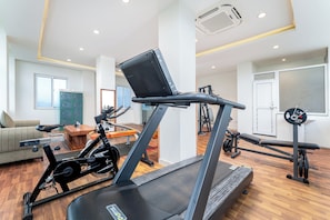 Ein Heim-Fitnessraum mit Laufband, Ergometer und Gewichtbank.