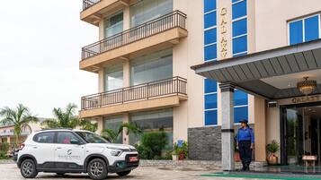 Un hotel a più piani con un cartello che riporta la scritta 'GALAXY' e un SUV bianco parcheggiato di fronte.