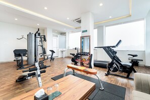 Ein Fitnessraum mit unterschiedlichen Trainingsgeräten, einer Bank und einem Spiegel.
