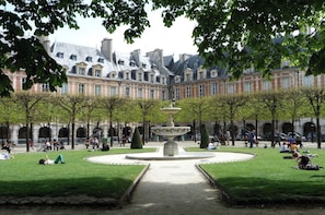 A courtyard with a central fountain, surrounded by a formal garden and classical architecture.