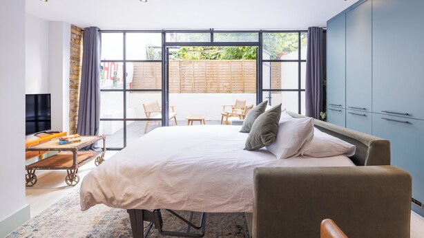 A modern bedroom with a large bed, a desk, and a TV. - Hackney 1 Bed Garden Flat Sleeps 4 Adults (London)