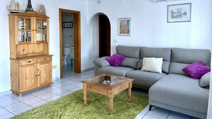 A living room with a grey sofa, a wooden cabinet, a green rug, and a glass coffee table. - Villa Canoa-3-d vistas al mar , piscina MT003 (Denia)