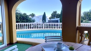 A terrace with a pool, white chairs, and a table with two cups and a small plant. - Villa Canoa-3-d vistas al mar , piscina MT003 (Denia)