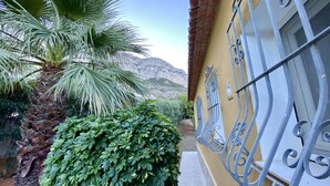 A balcony with a view of a mountain, a palm tree, and a hedge. - Villa Canoa-3-d vistas al mar , piscina MT003 (Denia)